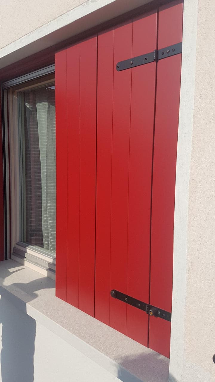 Persiana in legno verniciata rosso con bandelle nere e cardini